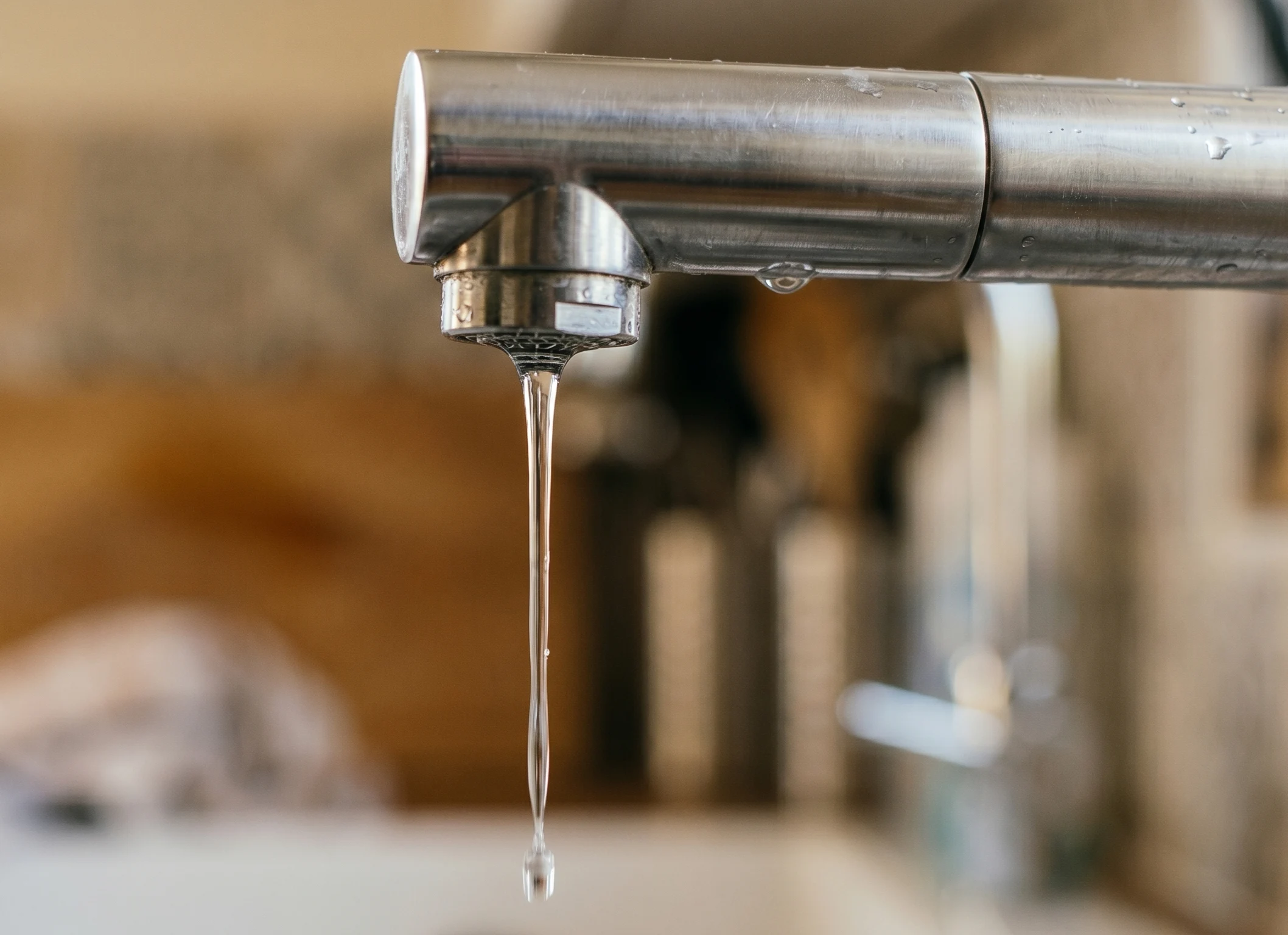 Grifo de cocina moderno con poca presión de agua soltando un hilo fino, ilustrando problemas de suministro en el hogar.