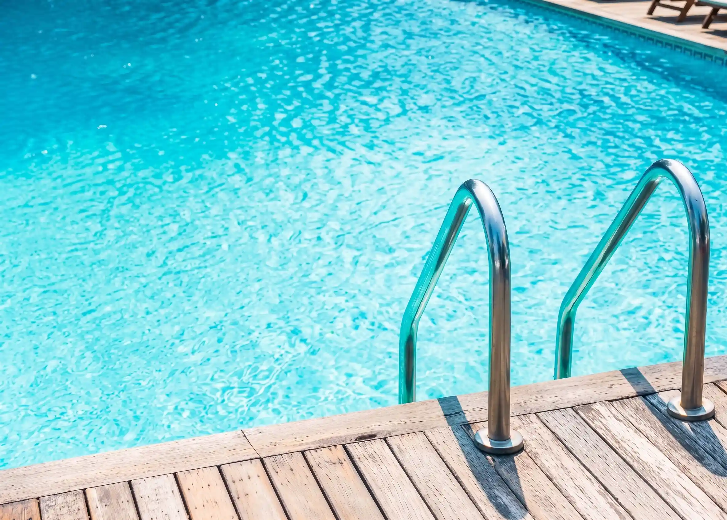 Piscina con agua cristalina y escaleras de acero inoxidable en una vivienda de la Sierra de Madrid, mantenida con sistemas de automatización.